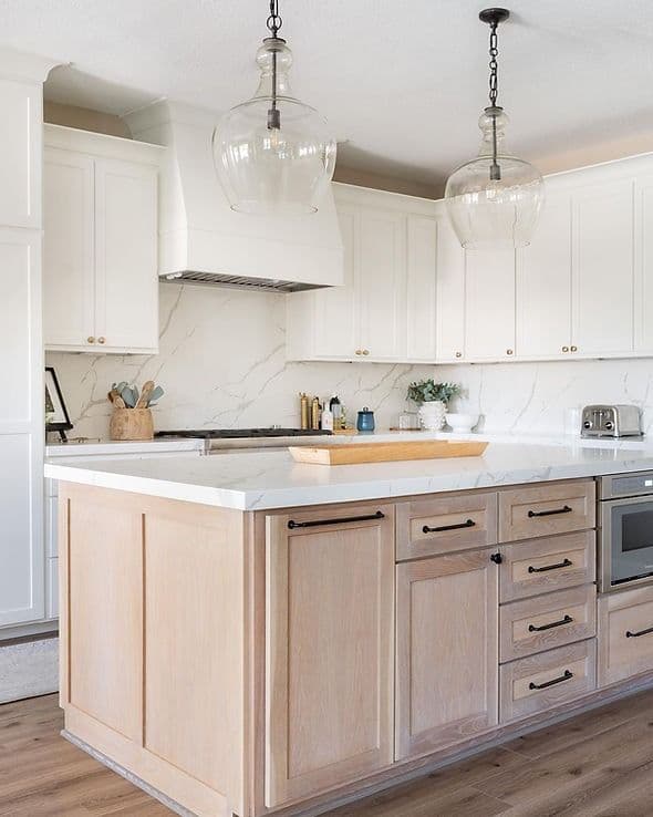 Quartz island with white oak cabinets and glass pendants